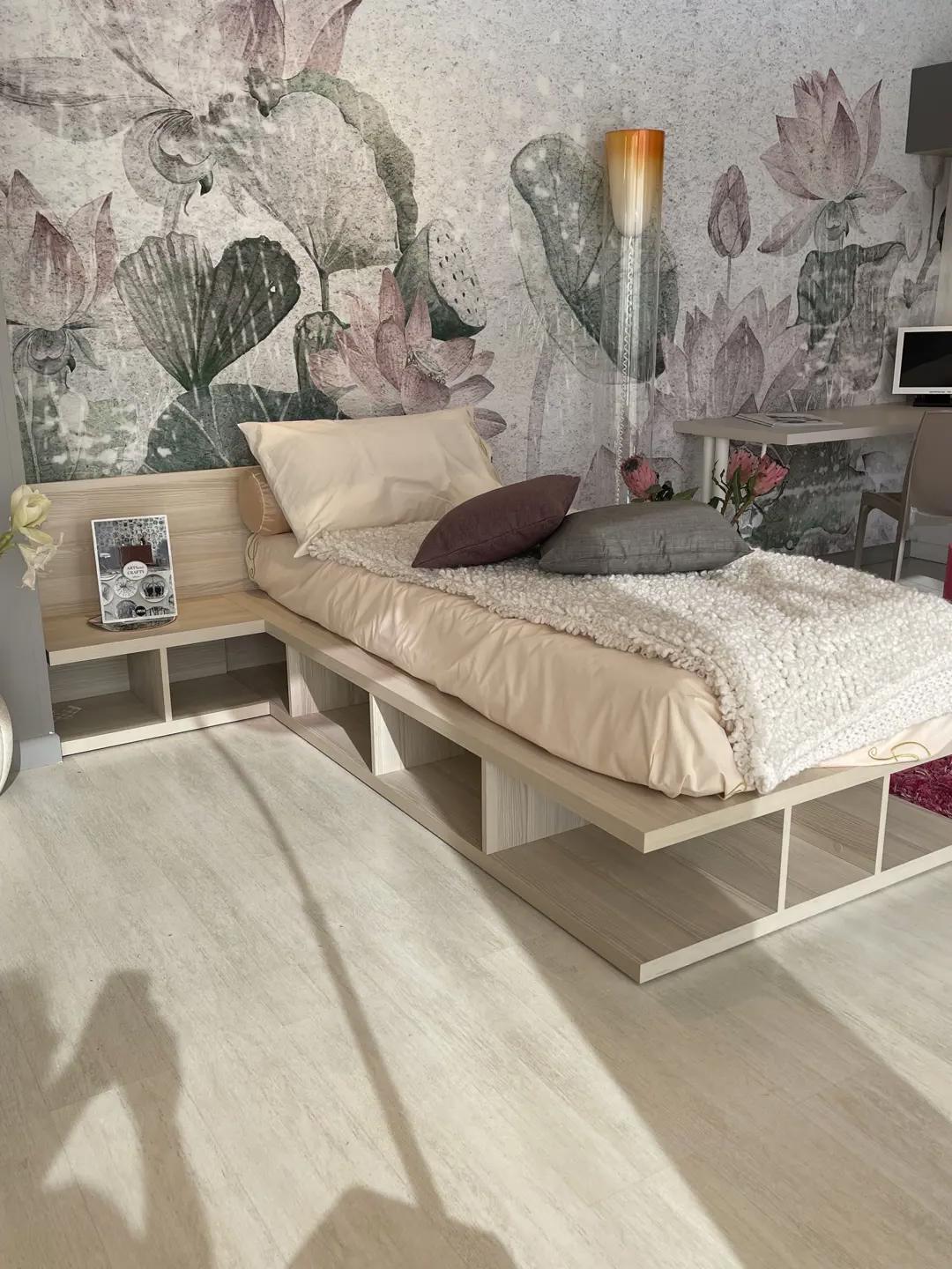 Letto singolo Montreal di Doimo Cityline in legno chiaro con base contenitore a vani aperti e comodino Lotus integrato nella testiera, esposto nello showroom Arredamenti Soldi a Follonica